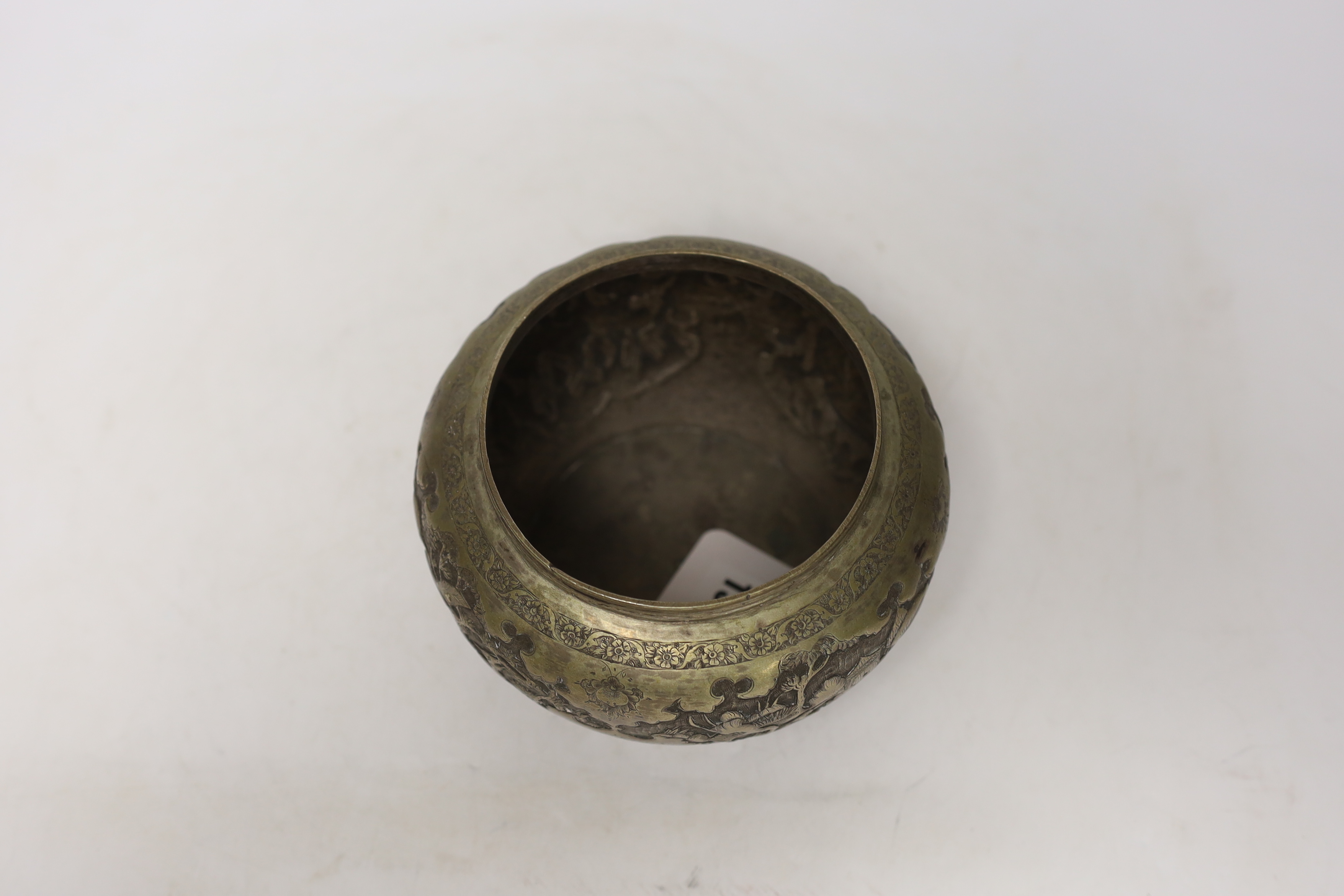 A Persian white metal bowl decorated in relief with animals and flowers, indistinct marks to the base, 16cm wide